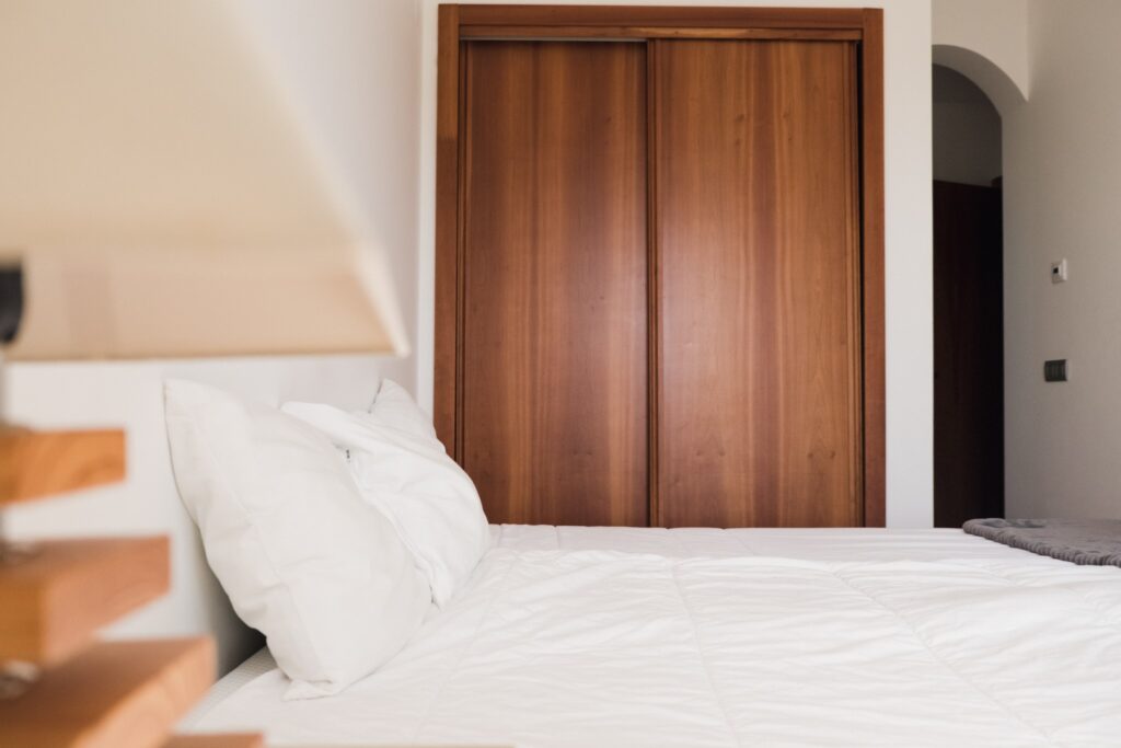 View of the bed of a double bedroom with private bathroom at POMAR coliving in Portugal.