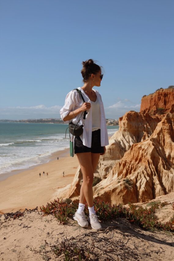 Farah, a digital nomad and coliver at POMAR Coliving, standing on a cliff overlooking Praia da Marinha, Algarve, Portugal
