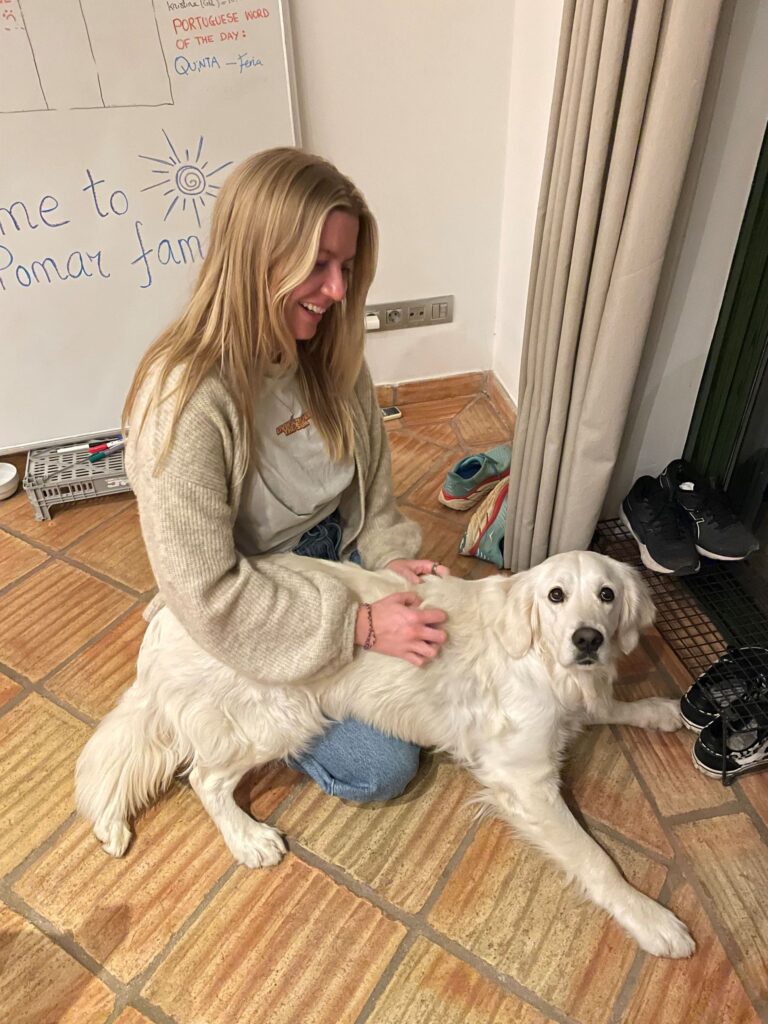 Amanda, a POMAR coliver, smiling while sitting on the floor with a friendly golden retriever