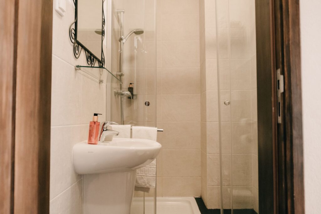 Compact and clean shared bathroom with shower, sink, and mirror at POMAR na praia.