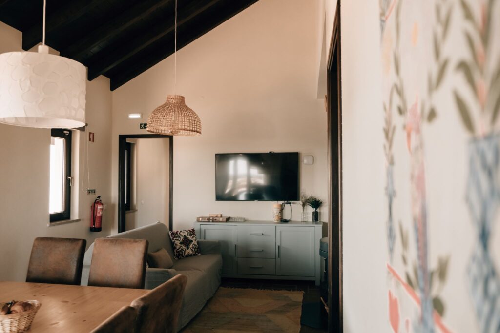 Cozy coliving living room at POMAR na praia with high ceiling, pendant lamps, smart TV and modern decor.
