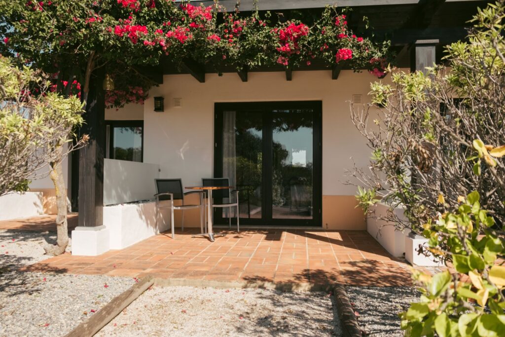 Private terrace with seating outside the suite at POMAR na praia, surrounded by blooming bougainvillea.