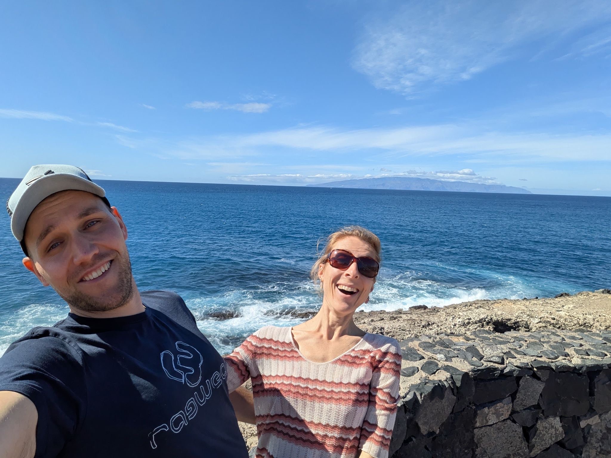 Couple smiling by the oceanfront with cliffs in the background
