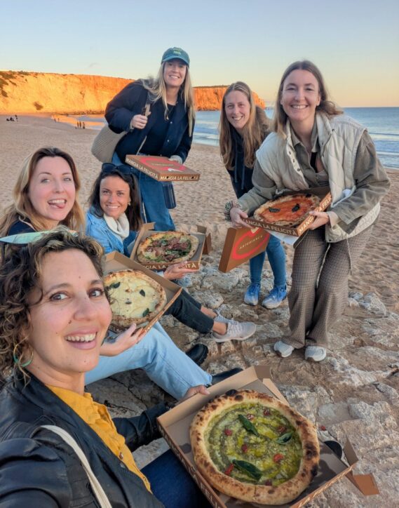 Group of colivers sharing gourmet pizza at the beach during sunset