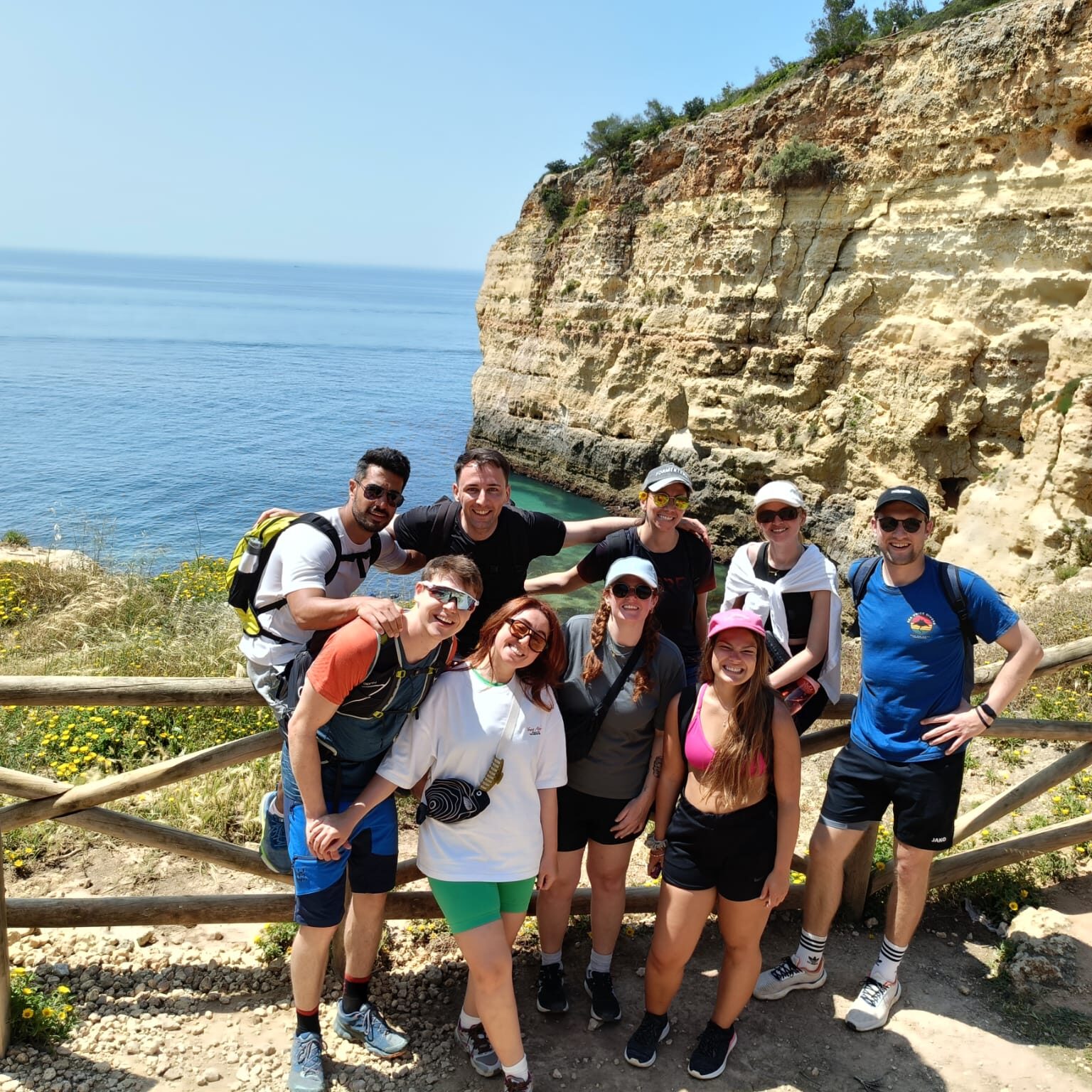 Group of smiling colivers standing on cliffs above the ocean during a hike near POMAR na praia