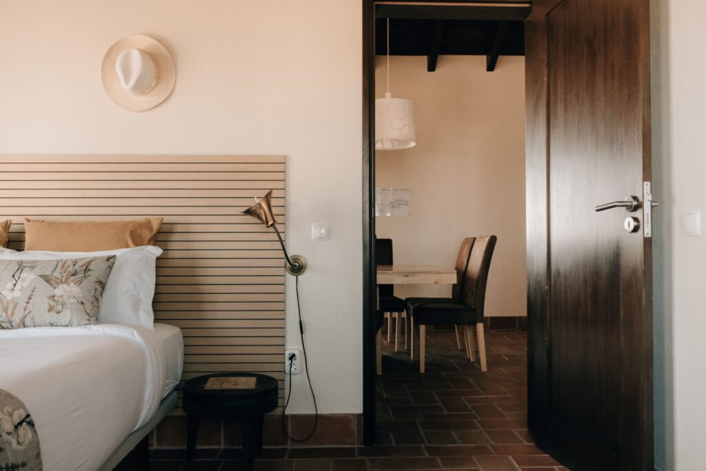Partial view of a cozy bedroom at POMAR na praia opening into a bright shared dining and living space