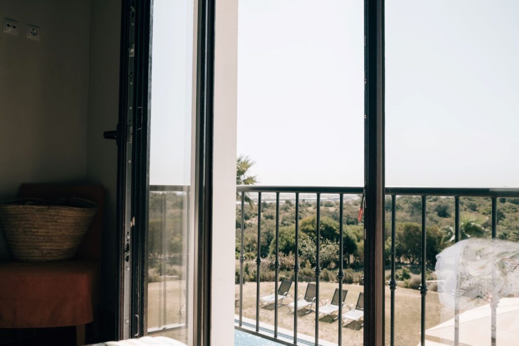 View from a bedroom at POMAR na praia overlooking pool loungers, trees, and the Algarve landscape