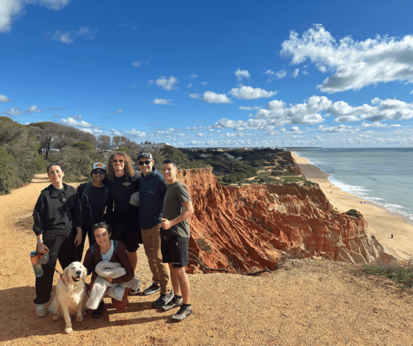 Group of people standing together on a coastal cliff in the Algarve with ocean views