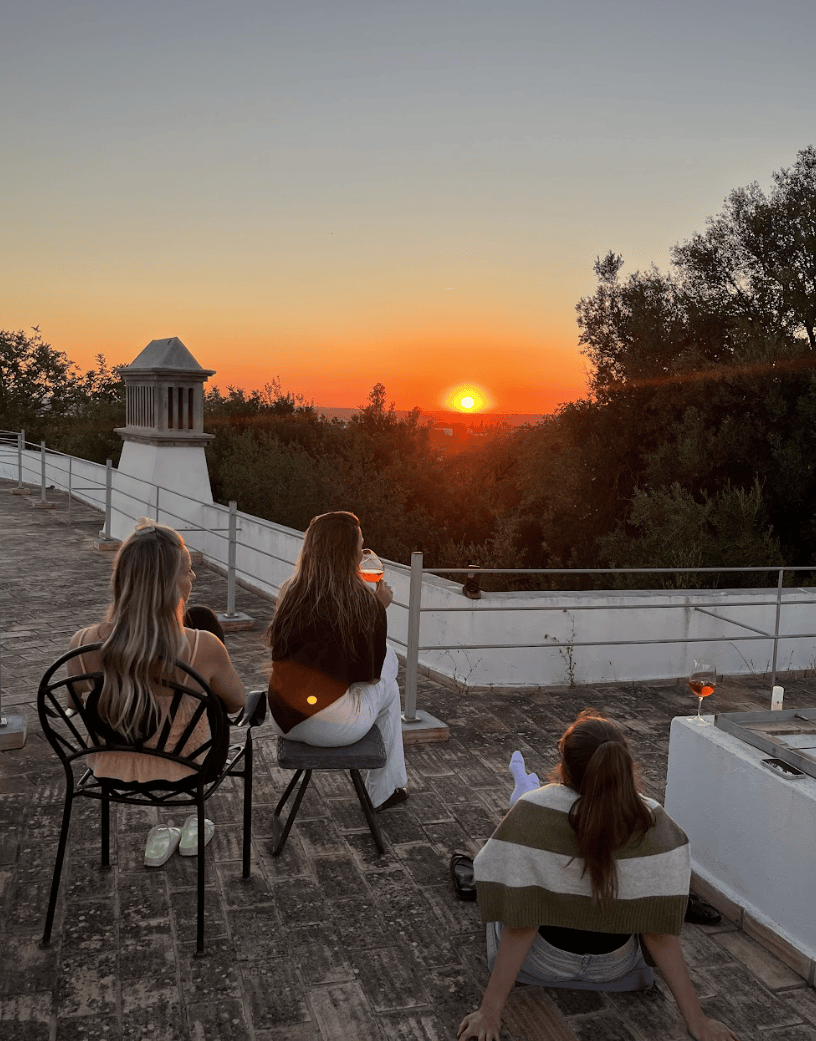 Sunset moment at POMAR Coliving Algarve Group of people sitting outdoors watching the sunset together at POMAR Coliving