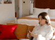 Woman relaxing on a sofa using her phone inside a cozy coliving living space
