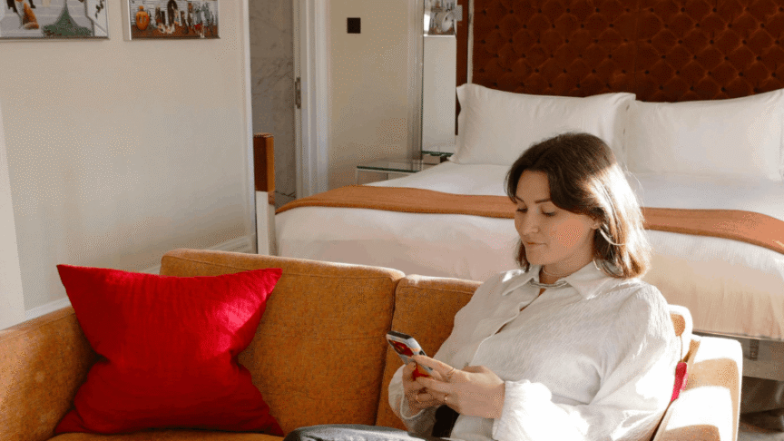 Woman relaxing on a sofa using her phone inside a cozy coliving living space