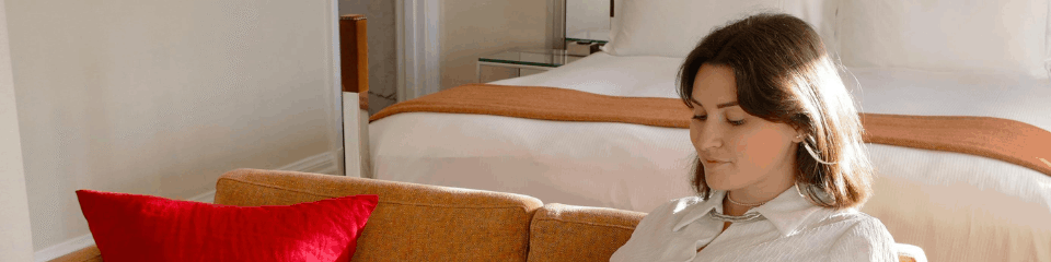 Quiet moment inside POMAR Coliving living room Woman relaxing on a sofa using her phone inside a cozy coliving living space