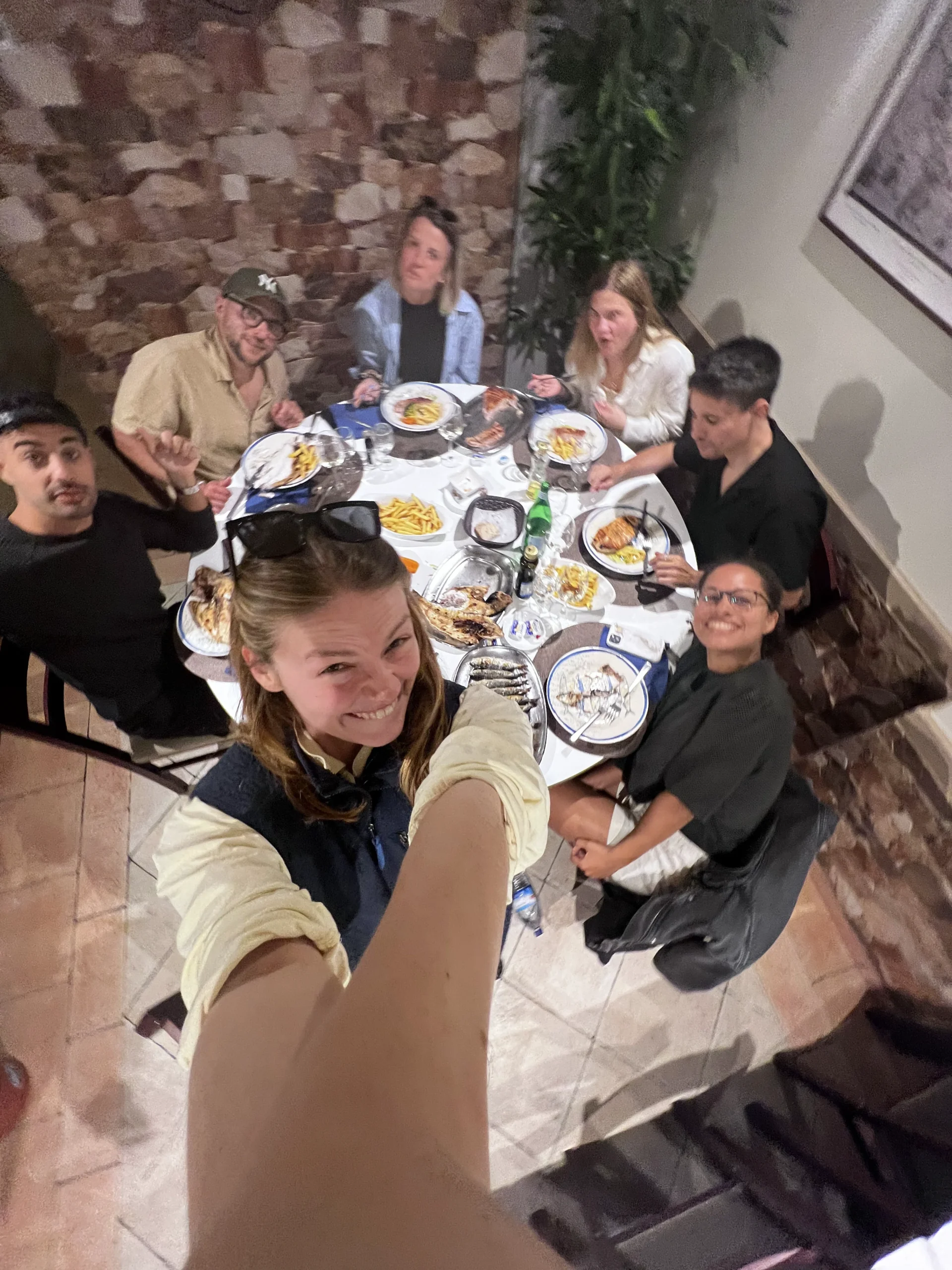People gathered around a dining table set with dishes, plates and glasses